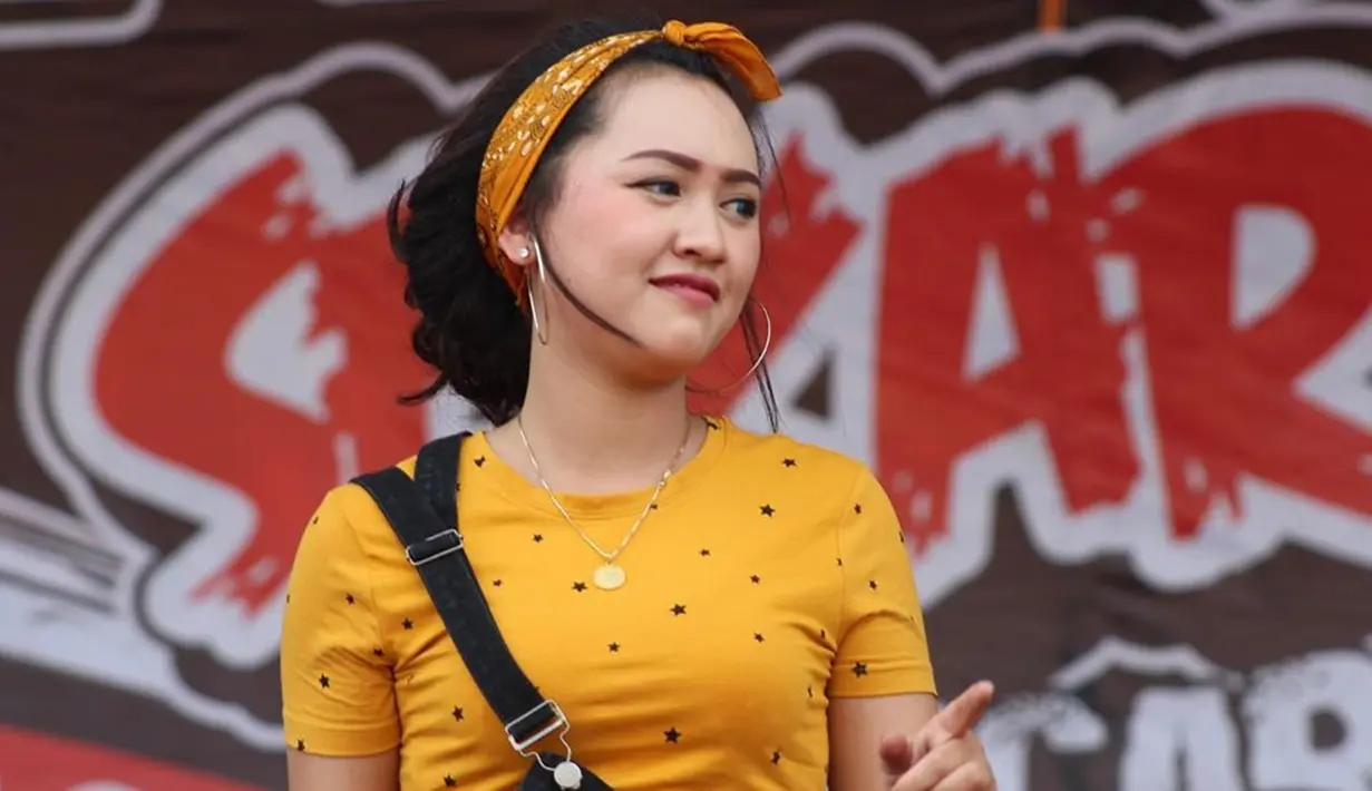 Pedangdut selalu identik dengan gaya glamor, namun di beberapa kesempatan wanita kelahiran Kediri, 10 Juni 1999 ini tak segan tampil dengan busana simpel. Saat bernyanyi di atas panggung, ia memilih mengenakan kaus berwarna kuning dengan motif bintang. (Liputan6.com/IG/@happy_asmara77)