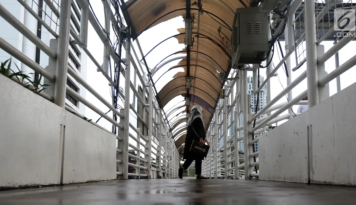 Warga melintasi Jembatan Penyeberangan Orang (JPO) yang rusak di kawasan Dukuh Atas, Jakarta, Rabu (12/12). Rusaknya JPO Dukuh Atas menggangu pejalan kaki yang melintas. (Liputan6.com/JohanTallo)