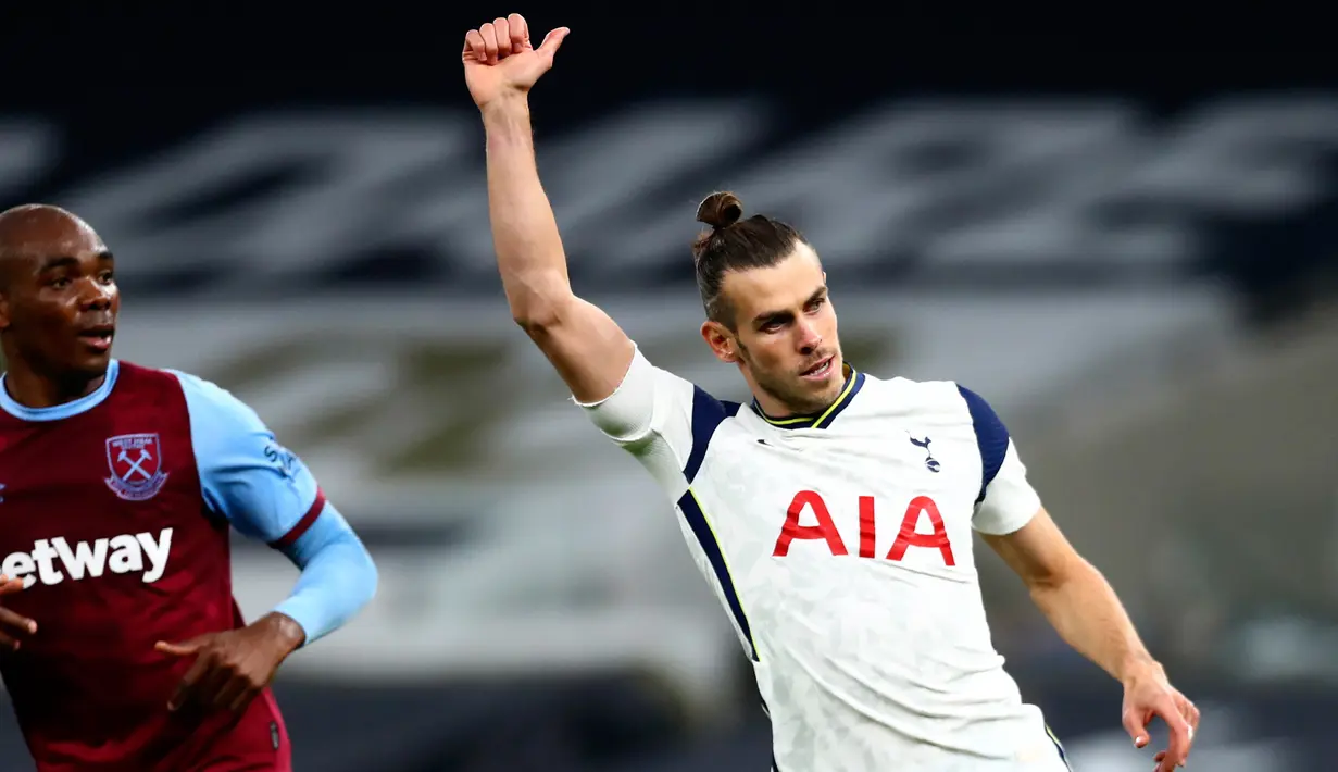 Penyerang Tottenham Hotspur, Gareth Bale memberikan gerakan di sebelah pemain West Ham, Angelo Ogbonna dalam laga Liga Inggris di Tottenham Hotspur Stadium, Minggu (18/10/2020). Laga yang berakhir dramatis 3-3 itu diwarnai debut bintang anyar Tottenham, Gareth Bale. (Clive Rose/Pool via AP)