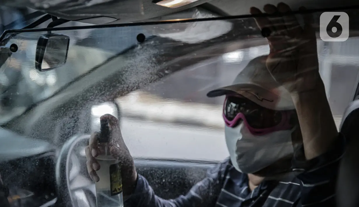 Pengemudi taksi daring, Aris Hardy Halim menyemprotkan disinfektan di dalam mobilnya di kawasan Bendungan Hilir, Jakarta, Jumat (8/5/2020). Pemasangan plastik pembatas antara pengemudi dengan penumpang tersebut bertujuan untuk mencegah penyebaran COVID-19. (Liputan6.com/Faizal Fanani)