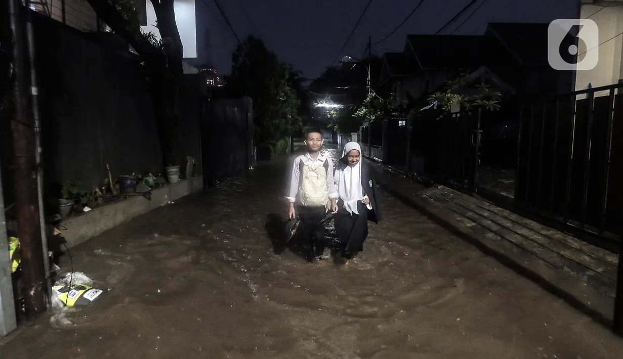 Warga melewati rumah yang tergenang banjir di jalan Bank, Jakarta Selatan, Selasa (4/10/2022). Hujan yang mengguyur wilayah Ibu Kota Jakarta mengakibatkan banjir menggenangi kawasan Kemang, Jakarta. (Liputan6.com/Johan Tallo)