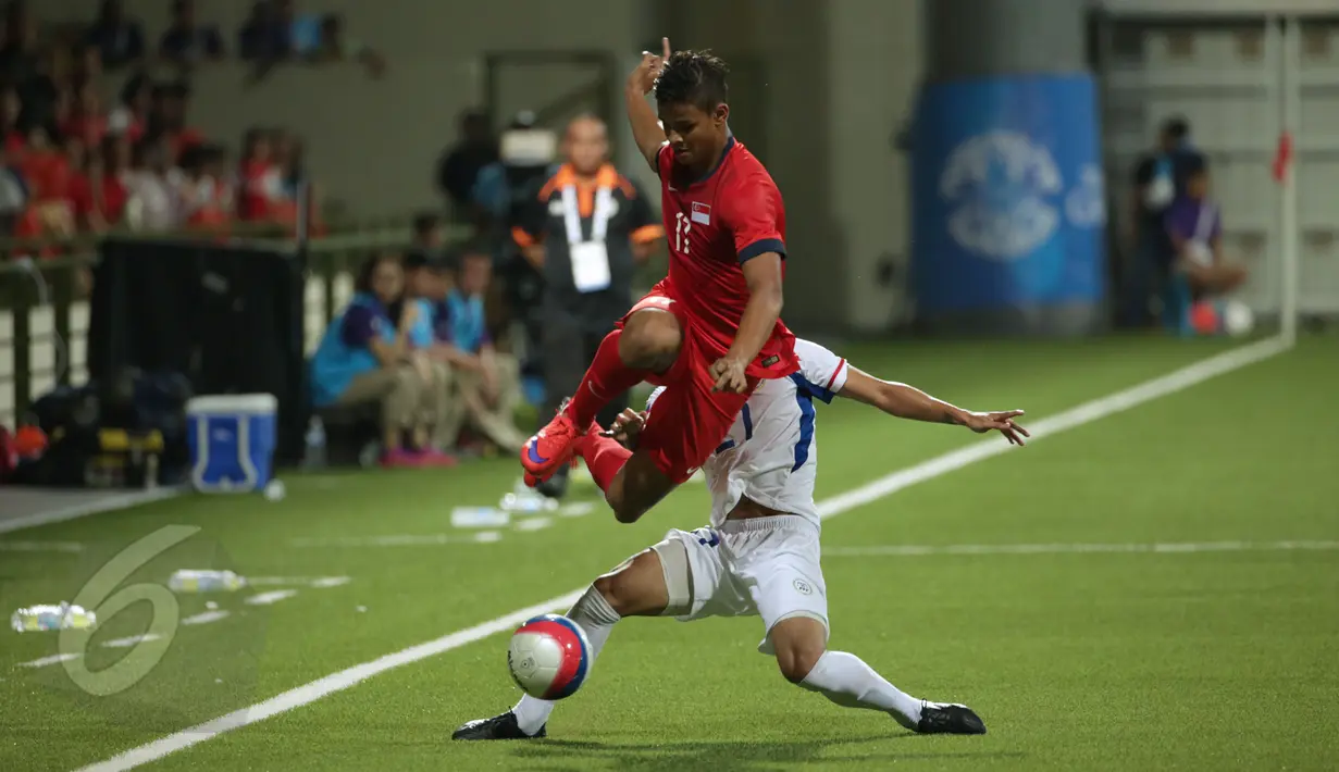 Pemain depan timnas Singapura U-23, Irfan Fandi Ahmad (kiri) melompat menghindari tackling pemain Filipina saat laga grup A Sea Games 2015 di Stadion Jalan Besar, Singapura, Senin (1/6/2015). Singapura unggul 1-0. (Liputan 6.com/Helmi Fithriansyah)
