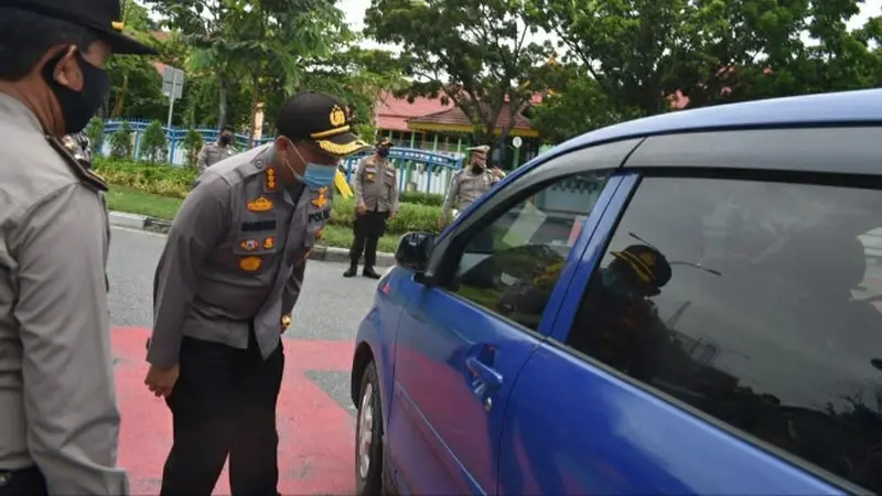 Personel Polda Riau mengecek pengemudi mobil terkait penerapan protokol kesehatan.