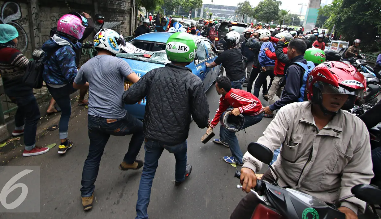 Sejumlah ojek online mengunakan batu merusak taksi di kawasan Senayan, Jakarta, Selasa (22/3). Pascabentrok ojek online melakukan sweeping dan perusakan terhadap taksi serta bajaj yang melintas di kawasan tersebut. (Liputan6.com/Immanuel Antonius)