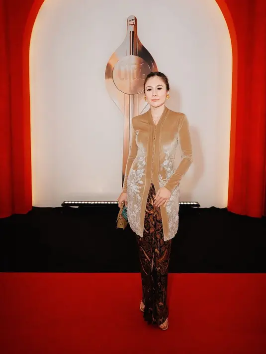 Wulan Guritno tampil dengan kebaya berbahan velvet warna coklat memiliki aksen bordiran di bagian bawah. Dipadukan kain batik coklat. [@snap.nuel]