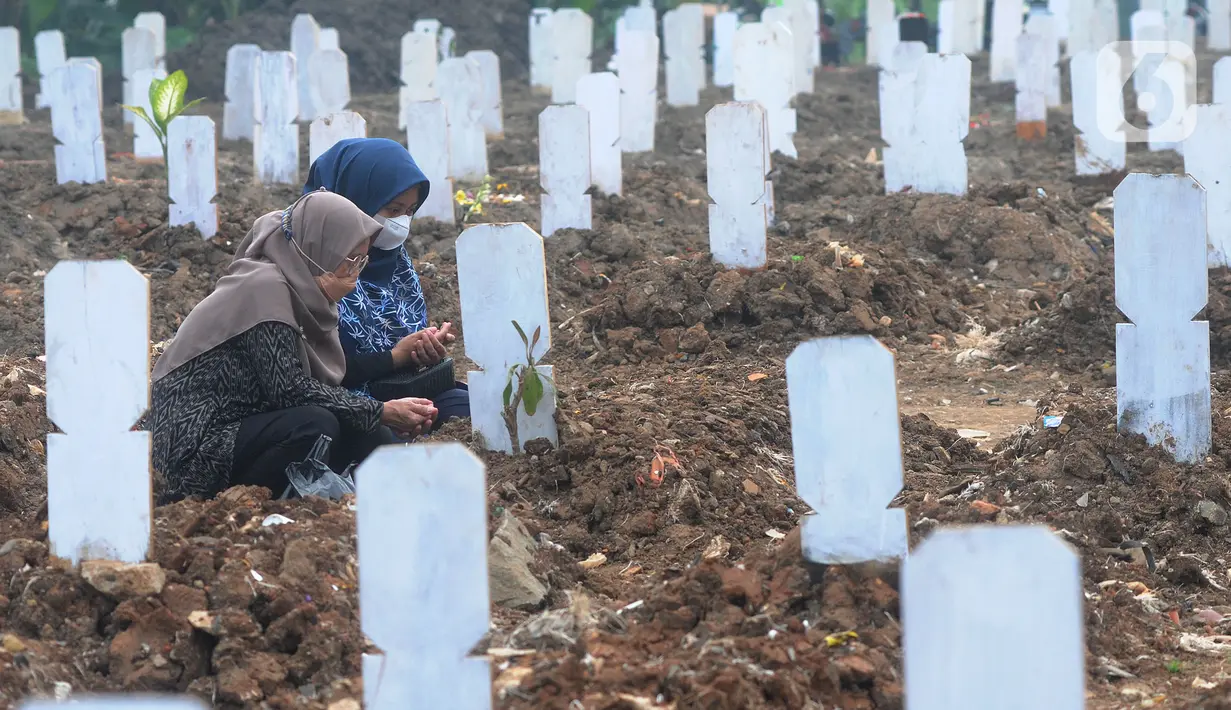 Keluarga berdoa depan pusara makam korban Covid-19 di TPU Srengseng Sawah 2, Jakarta Selatan, Jumat (19/3/2021). Seminggu terakhir intensitas pemakaman korban Covid-19 menurun drastis sebesar rata-rata 20 jenazah/minggu dibandingkan sebelumnya rata-rata 35 jenazah/minggu. (merdeka.com/Arie Basuki)