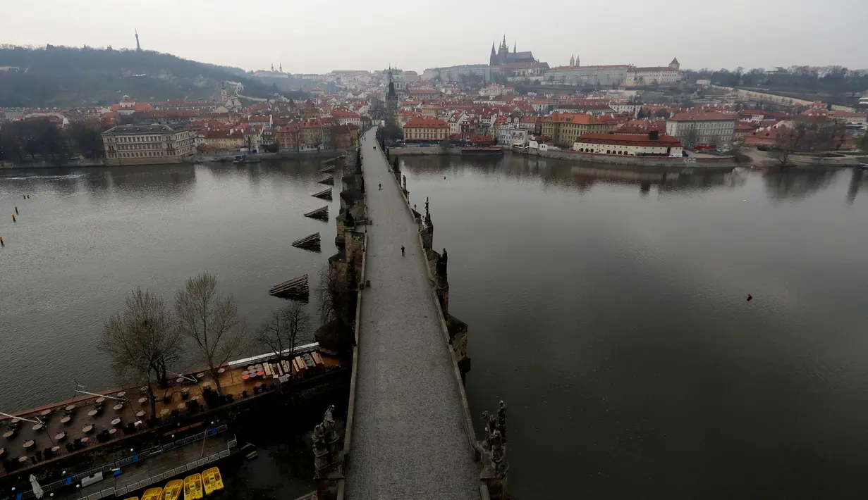 Pemandangan Jembatan Charles yang hampir kosong di Praha, Republik Ceko, Jumat, (20/3/2020). Pemerintah Republik Ceko telah menyetujui langkah dramatis lebih lanjut untuk mencoba dan membendung penyebaran virus corona baru yang disebut COVID-19. (AP Photo/Petr David Josek)