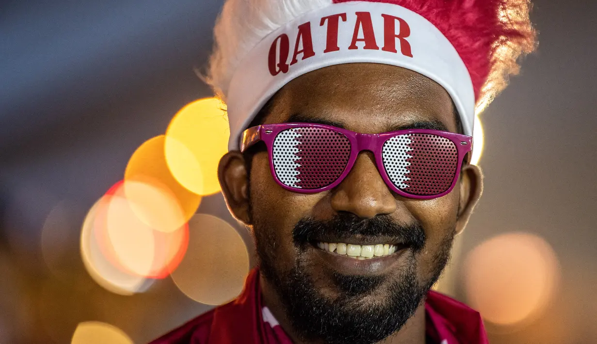 Seorang pendukung Qatar terlihat saat berkumpul dengan yang lain di luar hari pembukaan Festival Penggemar FIFA di taman Al Bidda di Doha pada 20 November 2022, saat pembukaan turnamen Piala Dunia Qatar 2022. (AFP/Philip Fong)
