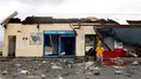 Seorang warga berjalan di depan sebuah bangunan yang rusak akibat Topan Nock-Ten di Mabini, Filipina (26/12). Topan super Nock-ten atau dikenal dengan Nina menerjang Filipina bertepatan saat Natal. (REUTERS/Erik De Castro)