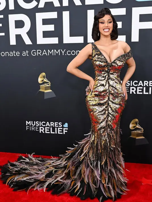 Untuk menyempurnakan penampilannya yang klasik nan mewah, Cardi menata rambut cokelat-nya dalam gaya ikal khas era Old Hollywood. Riasannya juga tidak kalah mencuri perhatian dengan tampilan bombshell makeup yang menonjolkan kecantikannya.  [@iamcardib].