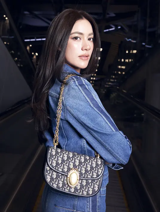 Ia menjinjing Dior Médaillon Flap Bag yang jadi statement piece pada penampilannya. [Dior]