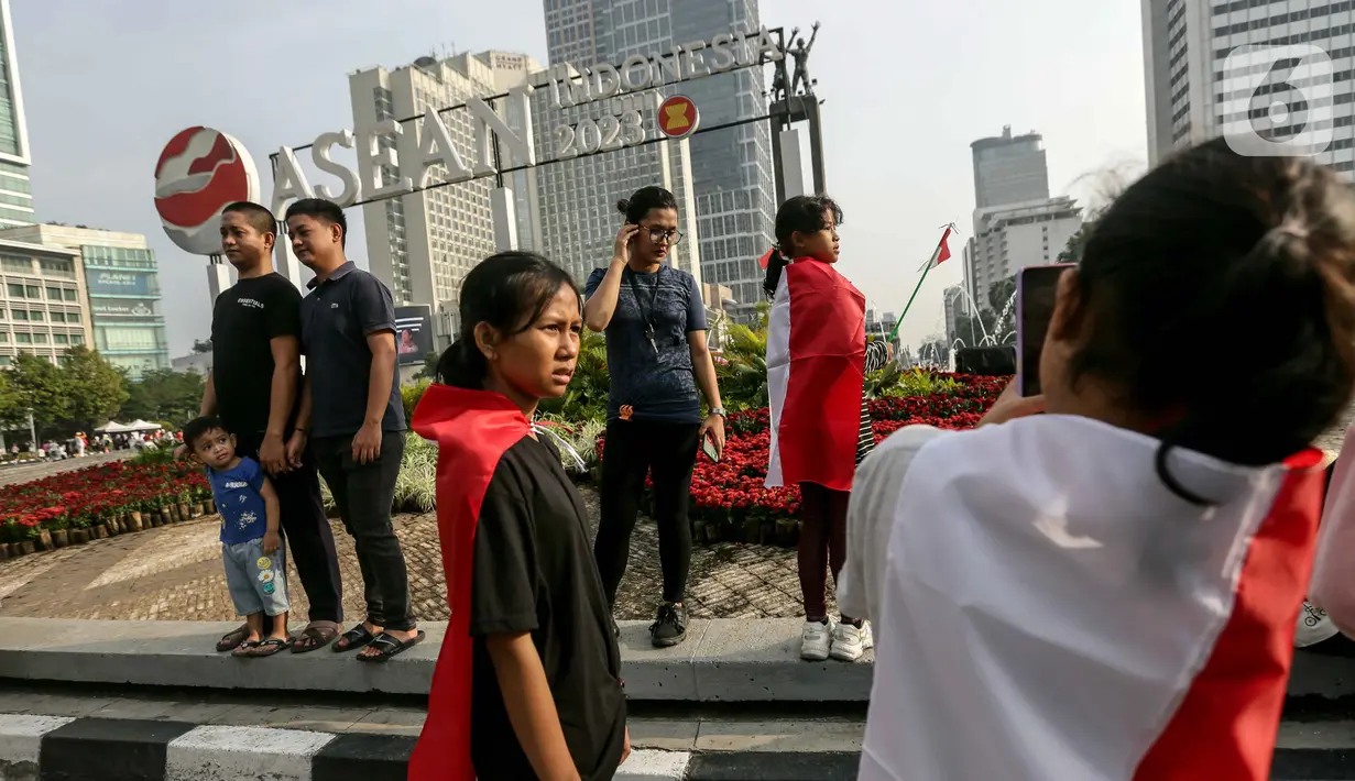 Warga yang mengenakan bendera Merah Putih untuk membalut tubuhnya berswafoto saat  CFD di Jakarta. (Liputan6.com/Faizal Fanani)