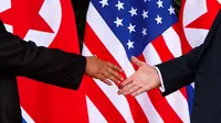Presiden Amerika Serikat (AS) Donald Trump menggapai tangan Pemimpin Korea Utara, Kim Jong-un untuk bersalaman dalam pertemuan bersejarah di resor Capella, Pulau Sentosa, Singapura, Selasa (12/6). (AP Photo / Evan Vucci)