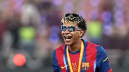 Pemain Barcelona, Lamine Yamal mengenakan dua kacamata saat merayakan gelar juara Piala Super Spanyol 2026 setelah mengalahkan Real Madrid dengan skor 3-2 dalam laga final yang berlangsung di King Abdullah Stadium, Jeddah, Arab Saudi, Minggu (11/01/2026) waktu setempat. (AFP/Fadel Senna)