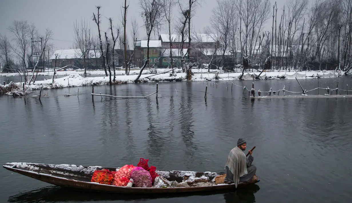 Pedagang berada di perahu membawa dagangannya  di pasar terapung di danau Dal, Srinagar, Kashmir India, (25/1). Pasar ini memulai aktivitasnya saat subuh dan selesai pada pukul 07.00. (AP Photo/Dar Yasin)
