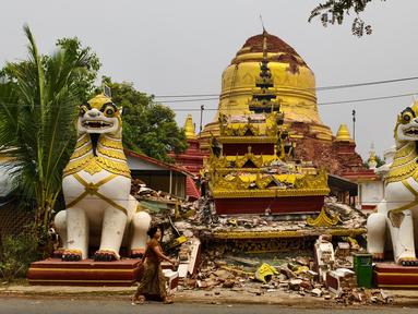 Seorang wanita berjalan melewati pagoda Buddha yang rusak di Inn Wa di pinggiran Mandalay pada 6 April 2025. (Foto oleh AFP)