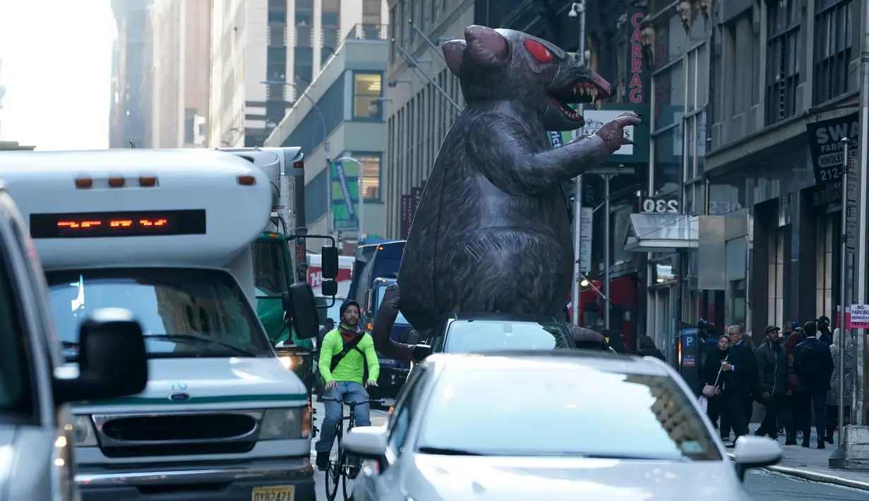 Balon tikus raksasa berjalan di tengah kota untuk diletakkan di luar kantor perusahaan sebagai simbol protes di New York, Kamis (26/12/2019). Serikat pekerja Amerika telah menggunakan balon tikus  untuk menyoroti praktik perburuhan yang tidak adil sejak 1990-an. (TIMOTHY A. CLARY/AFP)