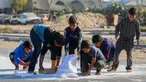 Anak laki-laki Palestina mengais tepung dari jalan setelah sebuah tas jatuh dari truk bantuan yang melaju di jalan Salaheddin di Deir el-Balah di Jalur Gaza tengah pada 5 November 2024. (Eyad BABA/AFP)