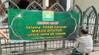 Seorang pengurus Masjid Jami Kota Malang memasang informasi tentang penutupan masjid untuk jamaah umum termasuk tak menggelar malam takbiran dan salat idul adha di masa PPKM Darurat.  (Dok Masjid Jami Malang)