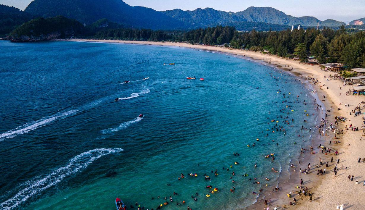 Di pantai ini pengunjung juga dapat menikmati suasana pantai yang asri. Tampak dalam foto, pemandangan udara menunjukkan orang-orang saat berkumpul menikmati masa libur panjang Idulfitri di area olahraga air, Pantai Lhoknga, Aceh, pada Kamis 26 Maret 2026. (Chaideer MAHYUDDIN/AFP)
