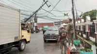 Tiang listrik hampir roboh imbas hujan lebat dan angin kencang di Jalan Raya Ciomas-Kreteg, Kecamatan Ciomas, Kabupaten Bogor, Jawa Barat, Selasa (31/10/2023) sore. (Liputan6.com/Achmad Sudarno)