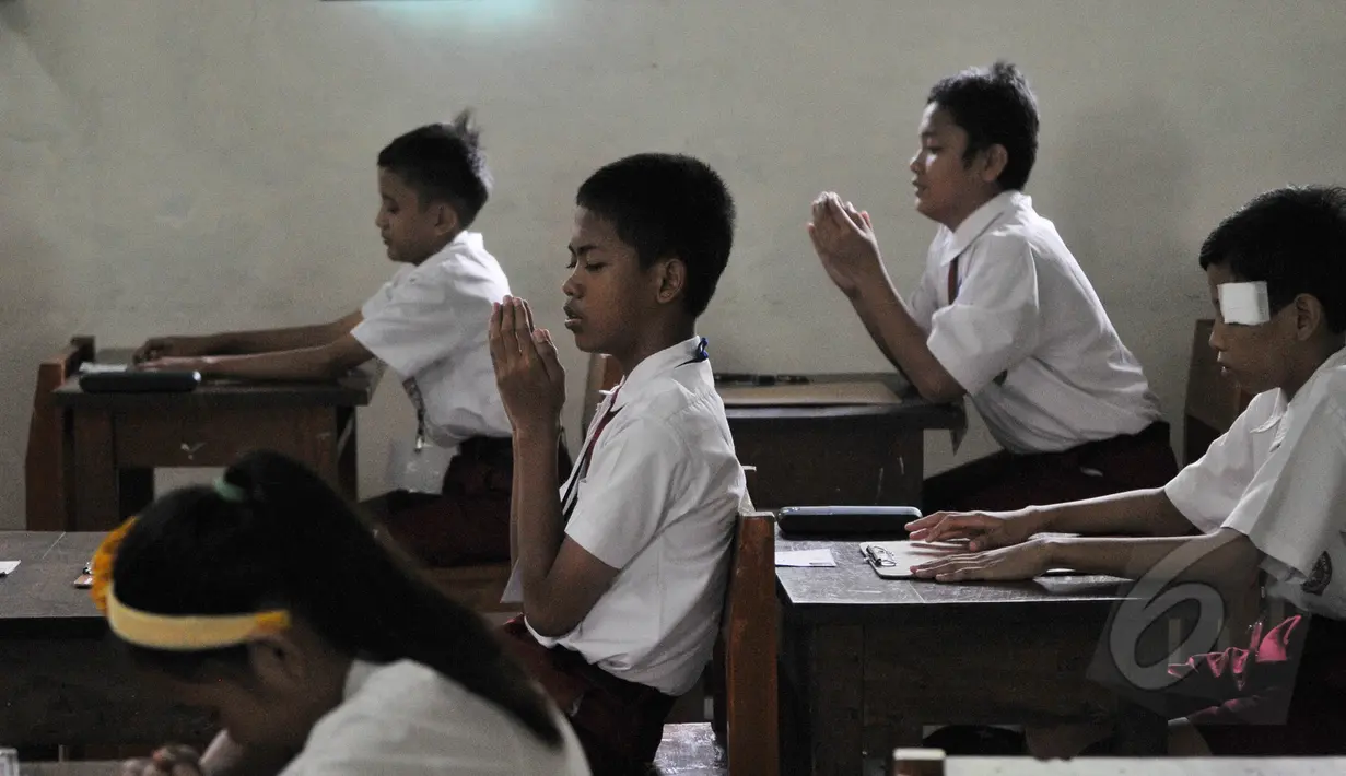Sejumlah peserta berdoa sebelum memulai Ujian Nasional (UN) di SDN 04 Jakarta, Senin (18/5/2015). Sebanyak 153.266 peserta didik SD/MI dan sederajat di Jakarta mengikuti UN yang digelar 18-20 Mei. (Liputan6.com/Herman Zakharia)