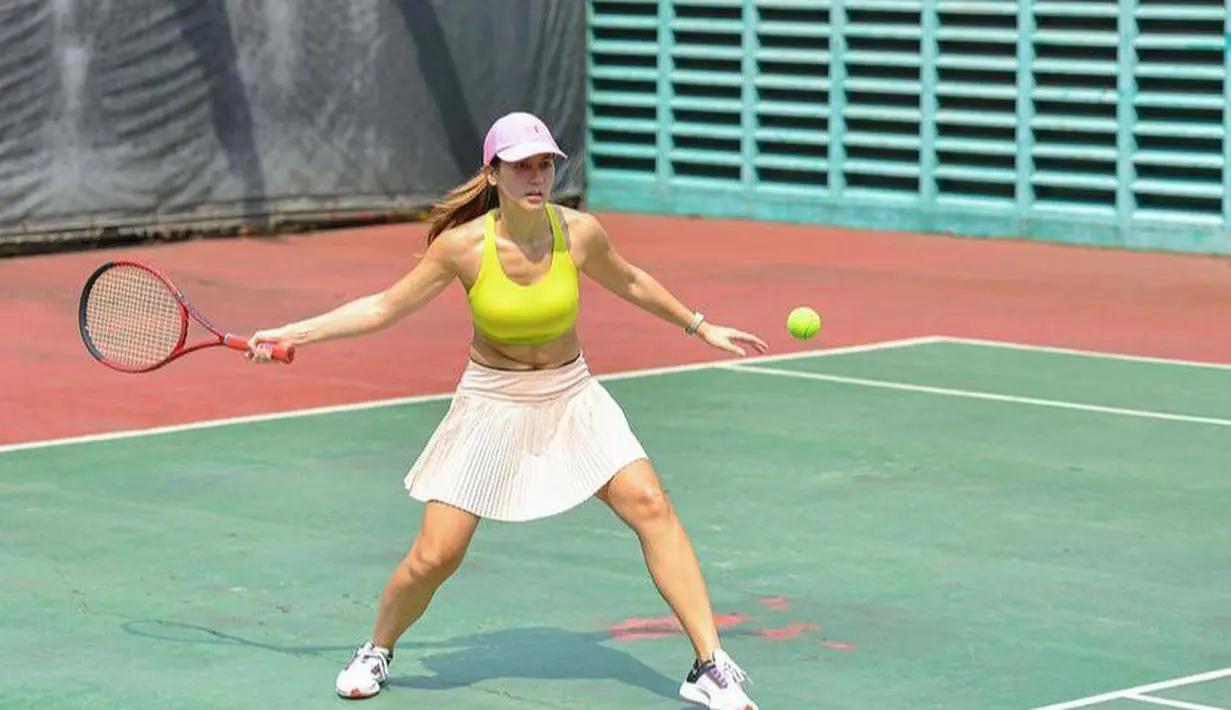 Masih dengan olahraga tenis, kali ini Pevita Pearce tampil cerah mengenakan tank top kuning, rok voli peach, dan topi pink. Ia melengkapi penampilannya dengan sepatu olahraga warna putih. @pevpearce.