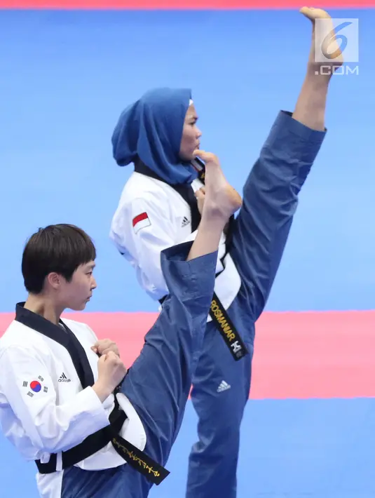 Atlet Taekwondo putri Indonesia, Defia Rosmaniar saat laga bersama Yun Jihye (Korea Selatan) pada Semifinal Women Individual Poomsae di JCC, Jakarta, Minggu (19/8). Defia Rosmaniar berhasil meraih emas. (Liputan6.com/Helmi Fithriansyah)