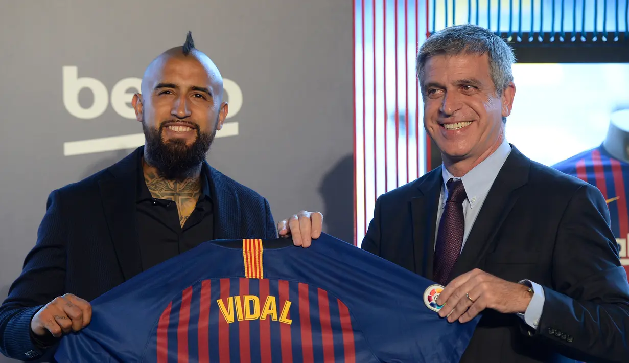 Pemain baru Barcelona, Arturo Vidal (kiri) berpose dengan Wakil Presiden Barcelona Jordi Mestre dalam presentasi resminya di Stadion Camp Nou, Barcelona, Spanyol, Senin (6/8). (Josep LAGO/AFP)