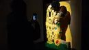 Seseorang mengambil gambar patung "Klimt kiss" yang terbuat dari susunan balok lego pada pameran Art of the Brick di Turin, Italia, Kamis (15/11). Pameran tersebut menampilkan berbagai patung lego karya seniman AS, Nathan Sawaya. (MARCO BERTORELLO/AFP)