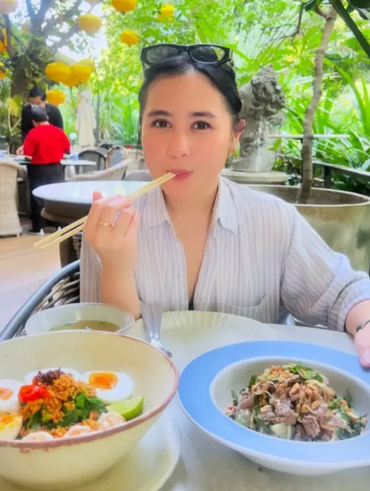 Menikmati makanan khas Thailand, Prilly tampil mengenakan kemeja bergaris dengan kancing terbuka. Kacamata frame hitam pun di letak di kepalanya.  [@prillylatuconsina96]