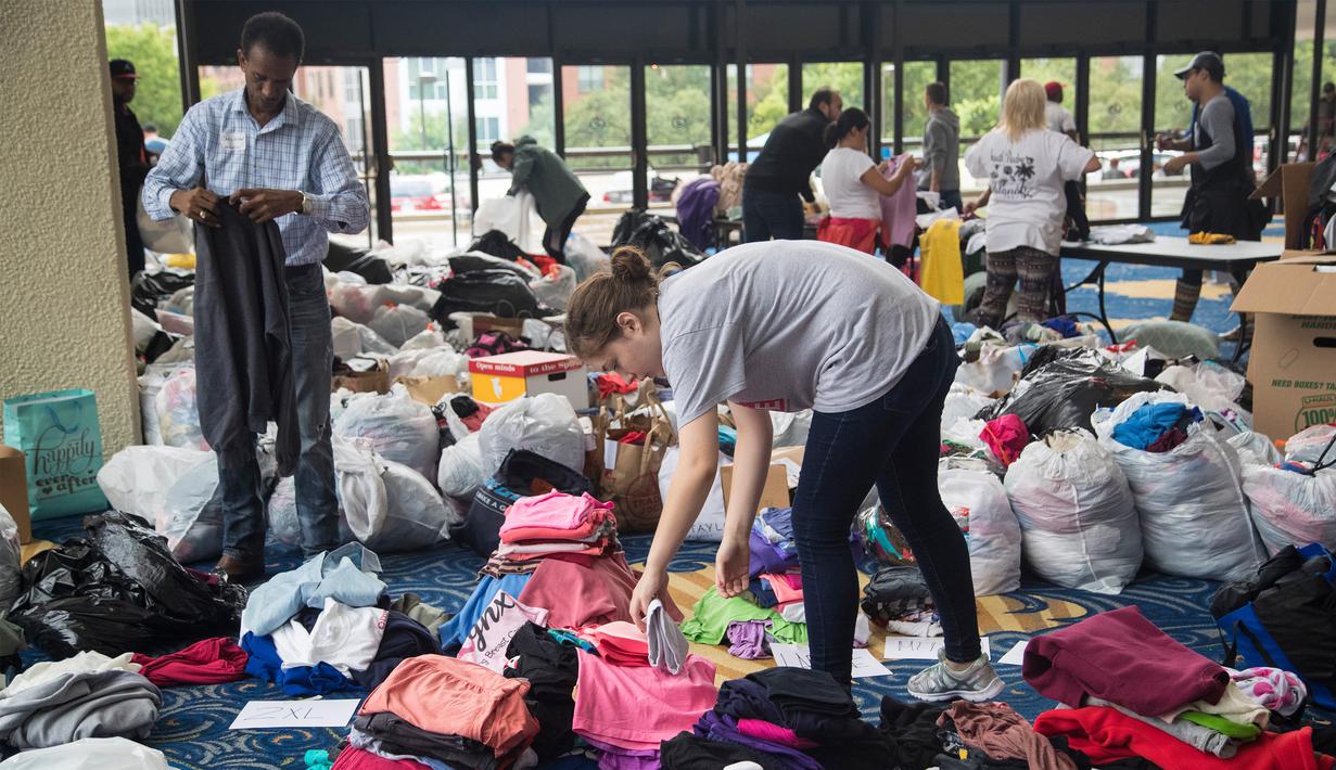Seorang relawan memilah baju hasil donasi sebelum dibagikan kepada korban Harvey di Houston, Selasa (29/8). Puluhan badan amal terpercaya lainnya turut membantu aksi penggalangan dana untuk korban Harvey. (Marie D. De Jesus/Houston Chronicle via AP)