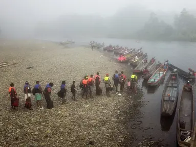 Para imigran mengantre untuk diangkut dari Desa Bajo Chiquito ke Migrants Reception Station di Lajas Blancas, Provinsi Darien, Panama, 23 Agustus 2021. Para imigran dari Haiti dan negara-negara lain tiba di wilayah Panama setelah berjalan kaki selama lima hari di Darien Gap. (Ivan PISARENKO/AFP)