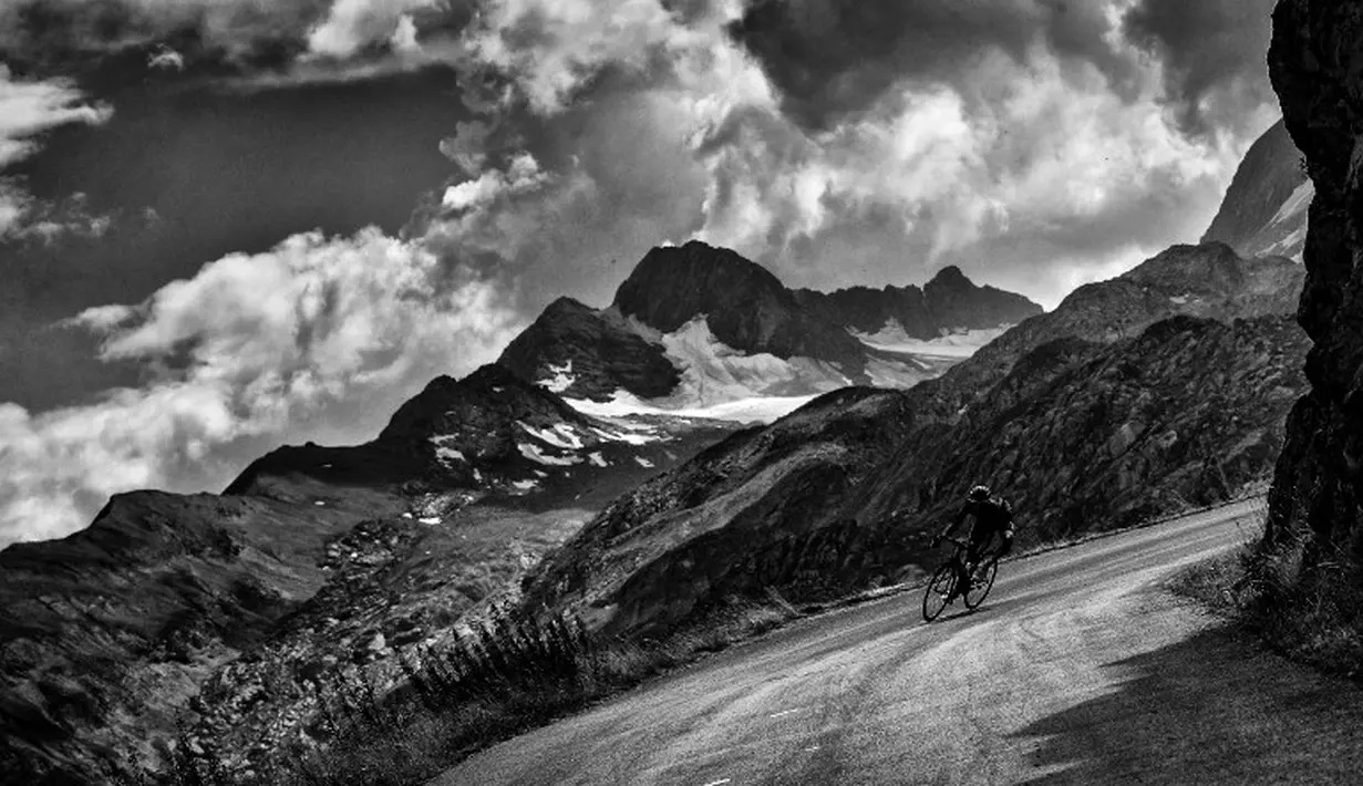 Aksi Pierre Rolland saat mengarung Etape 19 Tour de France dengan latar Pegunungan Alpen, Prancis. (AFP Photo/Jeff Pachoud)