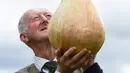 Peter Glazebrook berpose dengan bawang bombay seberat 6,6 kg yang berhasil memenangkan kelasnya ketika mengikuti kompetisi sayuran dan buah raksasa pada hari pertama Flower Show Autumn Harrogate, di Harrogate, Inggris, Jumat (15/9). (OLI SCARFF/AFP)