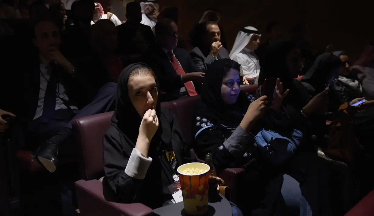 Seorang pengunjung perempuan memakan popcorn saat bersiap menyaksikan film Black Panther selama acara gala undangan di King Abdullah Financial District Theatre, Riyadh, Arab Saudi (18/4). (AFP Photo/ Fayez Nureldine)