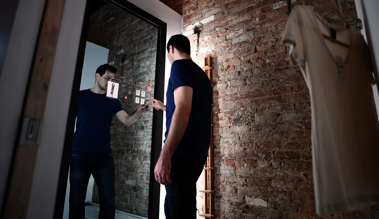 Wesley Bliss menunjukkan cara berinteraksi dengan cermin pintar Oak Fitting Room di sebuah butik, New York, AS (7/2). Cermin ini juga dapat mengukur tubuh sehingga merekomendasikan pakaian yang cocok. (AFP Photo / Jewel Samad)