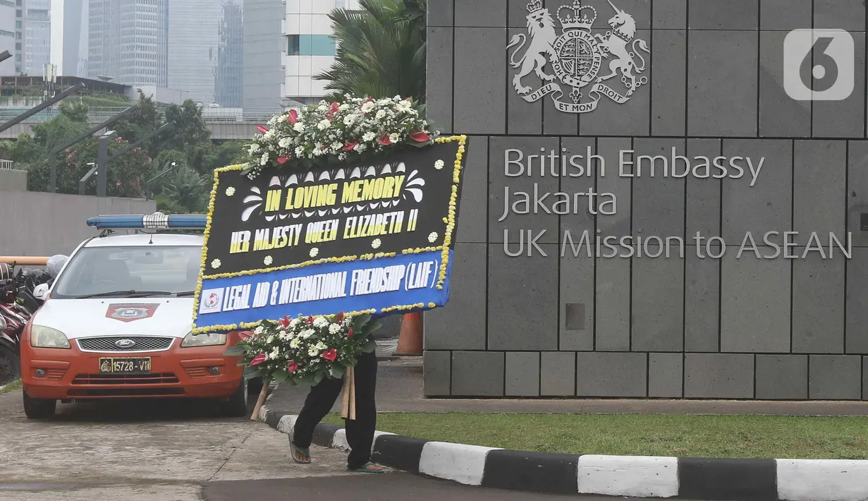 Petugas berjalan membawa karangan bunga duka cita atas meninggalnya Ratu Elizabeth II untuk diletakkan di depan Kedutaan Besar (Kedubes) Inggris, kawasan Kuningan, Jakarta, Jumat (9/9/2022).  Ratu Elizabeth II menghembuskan napas terakhir di rumah liburannya yakni Kastil Balmoral, Skotlandia. (Liputan6.com/Herman Zakharia)
