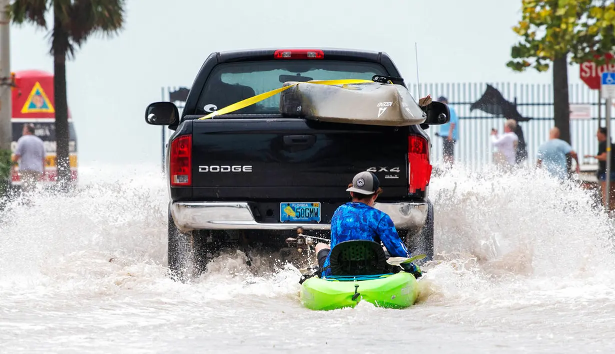 Sebuah truk menarik seorang pria di atas kayak di jalan dataran rendah setelah banjir karena Badai Ian, Key West, Florida, Amerika Serikat, 28 September 2022. (AP Photo/Mary Martin)