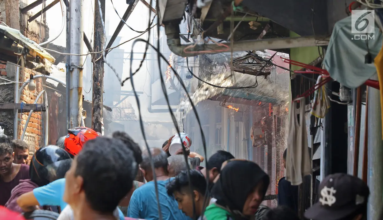Sejumlah warga berusaha memadamkan api membakar pemukiman padat penduduk di kawasan Manggarai, Jakarta, Rabu (10/7/2019). Belum diketahui pasti penyebab api membakar pemukiman warga tersebut. (Liputan6.com/Herman Zakharia)
