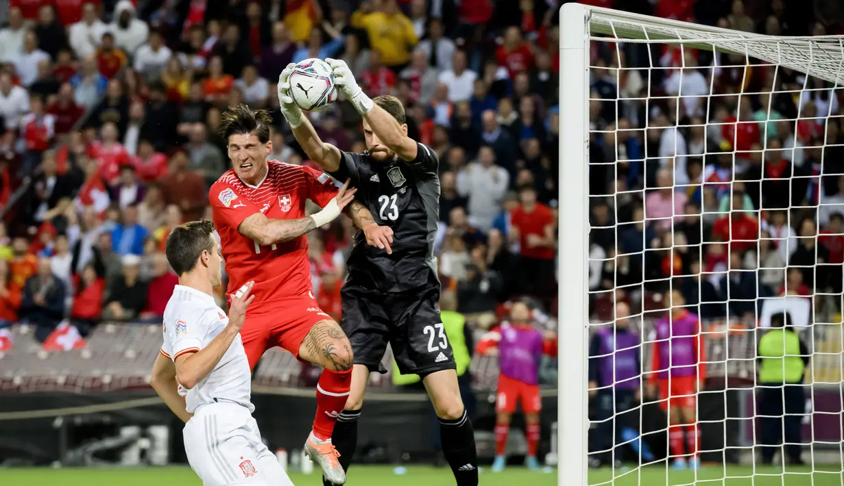Pemain Swiss Steven Zuber (kiri) berebut bola dengan kiper Spanyol Unai Simon (kanan) pada pertandingan sepak bola UEFA Nations League di Stadion Stade de Geneve, Jenewa, Swiss, 9 Juni 2022. Spanyol menang 1-0. (Jean-Christophe Bott/Keystone via AP)
