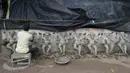 Perajin membuat patung Dewa Ganesha di sebuah bengkel di pinggiran Hyderabad, India, Rabu (18/8/2021). ​Patung ramah lingkungan yang dibuat jelang perayaan Ganesh Chaturthi tersebut dibuat dari lumpur, serat rami, dan bambu untuk mengurangi polusi air. (NOAH SEELAM/AFP)