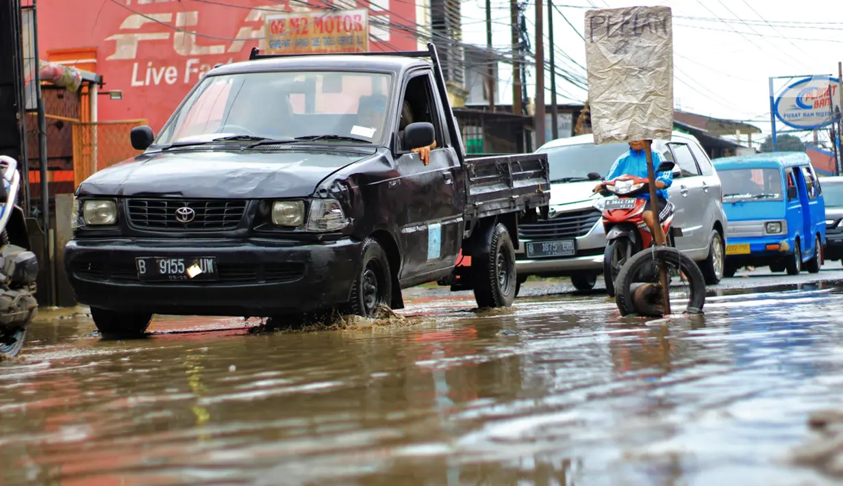 Sejumlah pengendara melintasi jalan berlubang dan tergenang air di Jalan Raya Pabuaran, Citayam, Depok, Rabu (26/2/2020). Kerusakan disebabkan oleh kubangan air yang menggenangi jalan tersebut pada musim hujan  yang melanda Jabodetabek dua bulan terakhir. (merdeka.com/magang/Muhammad Fayyadh)