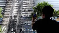 Seorang penghuni apartemen mengambil gambar Gedung Neo Soho pasca kebakaran di Tanjung Duren, Jakarta, Kamis (10/11). Kebakaran Gedung yang masih dalam tahap pembangunan itu terjadi Rabu (9/11) sekitar pukul 20.30. (Liputan6.com/Gempur M. Surya)