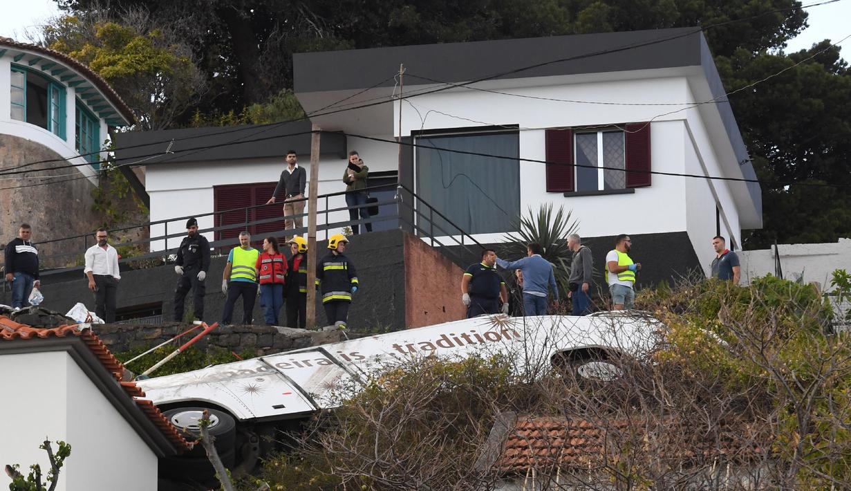 Orang-orang melihat kondisi sebuah bus pariwisata berisi rombongan turis dari Jerman yang terguling di Kota Canico, Pulau Madeira, Portugal, Rabu (17/4). Warga setempat melaporkan bahwa cuaca baik-baik saja pada saat kecelakaan, yang terjadi di sore hari. (RUI SILVA / AFP)
