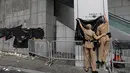 Petugas menutupi tembok yang dirusak oleh pengunjuk rasa dengan selembar plastik di pintu masuk utama kantor polisi di Hong Kong, Sabtu (22/6/2019. Ribuan pengunjuk rasa sempat mengepung markas polisi tersebut dan melemparinya dengan serta menuliskan kata-kata di dinding luar. (AP Photo/Vincent Yu)