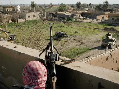 Anggota Syrian Democratic Forces (SDF) mengintai militan ISIS dari sebuah bangunan di kantong terakhir kekhalifahan di Baghouz, Suriah, Senin (18/2). ISIS dilaporkan kian terkepung. (AP Photo/Felipe Dana)