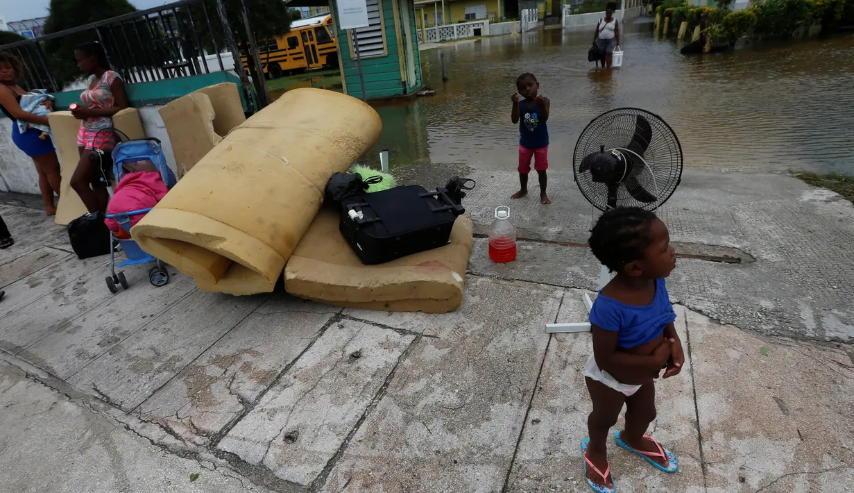 Sejumlah warga menunggu bantuan setelah hantaman Badai Earl yang mengakibatkan rumah-rumah terendam banjir di Kota Belize, Belize (4/8). Badai Earl membawa angin kecepatan 130 km per jam. (REUTERS/Luis Echeverria)