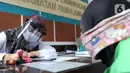 Petugas Dinas Kependudukan dan Catatan Sipil menggunakan pelindung wajah saat melayani warga di Kecamatan Pamulang, Tangerang Selatan, Rabu (3/6/2020). Sejumlah kantor pelayanan pemerintah melaksanakan protokol kesehatan yang ketat untuk memutus rantai penyebaran covid-19. (merdeka.com/Arie Basuki)