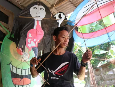 Perajin menyelesaikan pembuatan layang-layang Koang di Bedahan, Depok, Jawa Barat, Senin (20/7/2020). Kerajinan layangan berbahan rangka bambu, plastik, dan kain ramai diburu pada musim kemarau. (Liputan6.com/Fery Pradolo)